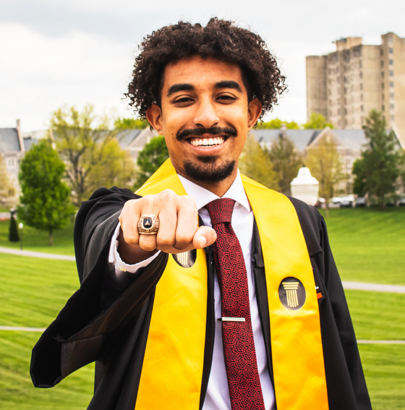 Senegal Ghidewan highlighting his class ring with his graduation robes