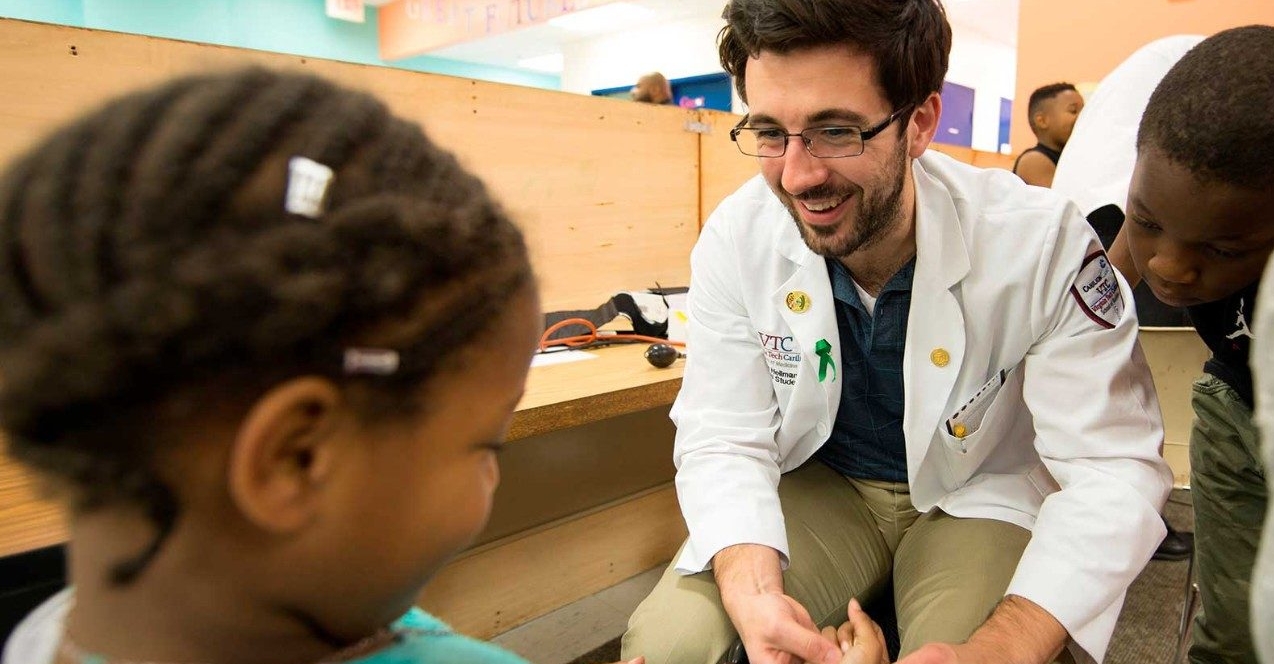 A med student works with children on a demonstration